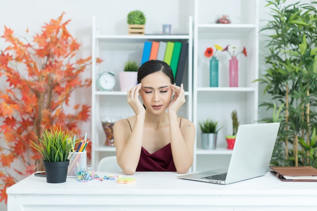 Jonge mooie vrouw die hoofdpijn heeft die aan computer thuis werkt Gratis Foto