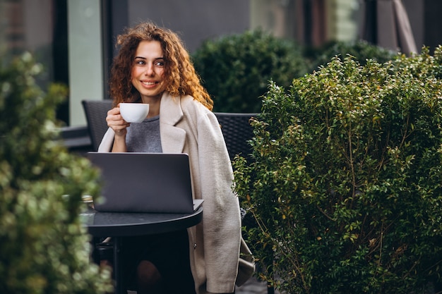 Jonge onderneemster die aan een computer buiten het koffie werkt Gratis Foto