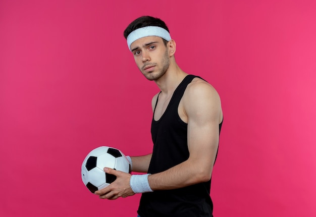 auditorium Rendezvous Datum Jonge sportieve man in hoofdband met voetbal met ernstige uitdrukking  staande over roze muur | Gratis Foto