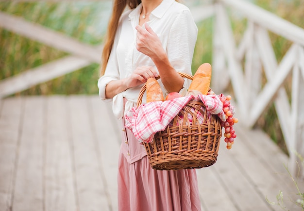 transfusie matchmaker Treinstation Jonge vrouw blonde met lang haar in retro-stijl vintage kleding staat met  een picknickmand op een houten pier van het meer | Premium Foto