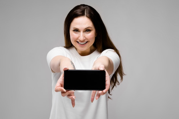 Jonge vrouw die telefoon voorstelt Premium Foto