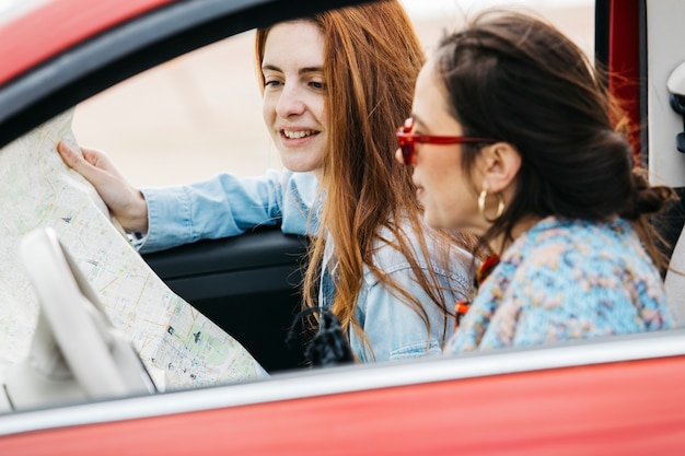 Jonge vrouwen die in auto zitten en kaart bekijken Gratis Foto