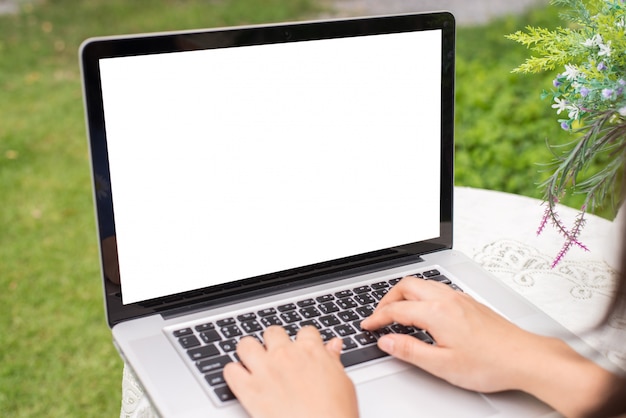 Jonge vrouwen die laptop computer op lijst met behulp van bij tuin. kijkzijde. bespreek scherm vrije ruimte voor uw ontwerp Gratis Foto