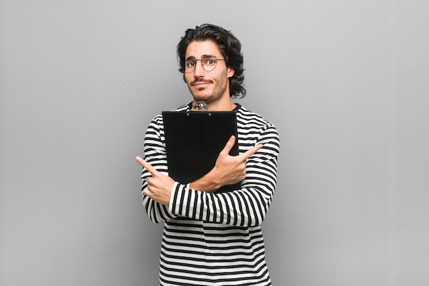 Jonge werknemer man met een inventaris opzij, probeert te kiezen tussen twee opties. Premium Foto