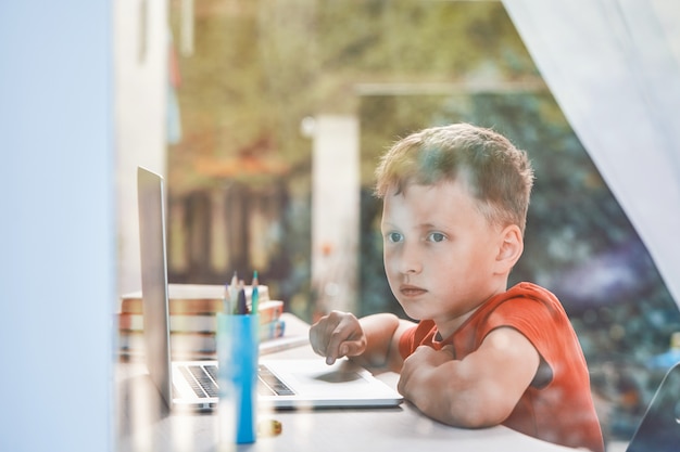 Kind wordt afgeleid van zijn studie en kijkt uit het raam Premium Foto