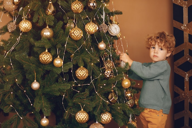 Kleine jongen in de buurt van de kerstboom in een grijze trui Gratis Foto