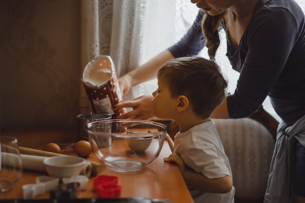Kleine jongen in de keuken helpt moeder om te koken. het kind is betrokken bij het koken. Gratis Foto