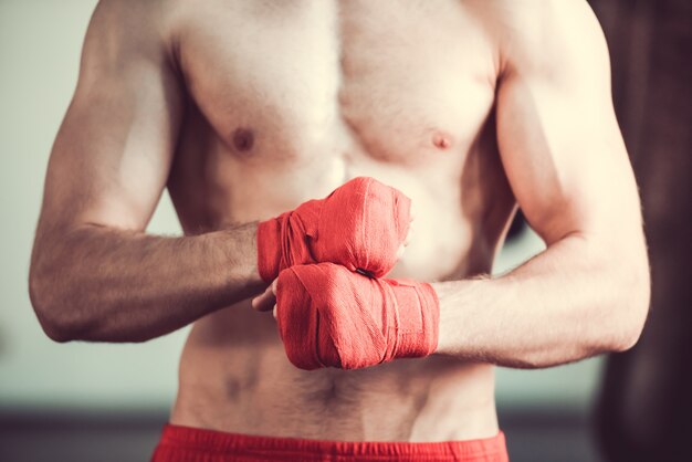 Knappe bebaarde bokser met blote torso die zijn handen inpakt. Premium Foto