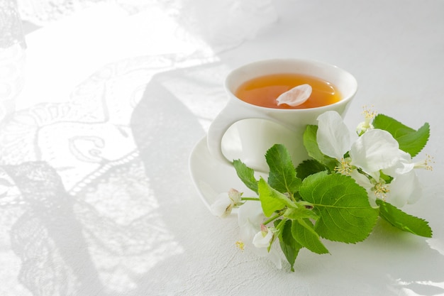 Kopje thee op een lichte tafel in de buurt van een raam in de ochtend en trossen bloemen met een kopie ruimte Premium Foto
