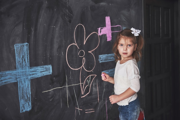 Krullend Weinig Babymeisje Dat Met Kleurpotloodkleur Op De Muur Trekt Werk Van Kind Leuke Leerling Die Op Bord Schrijft Premium Foto