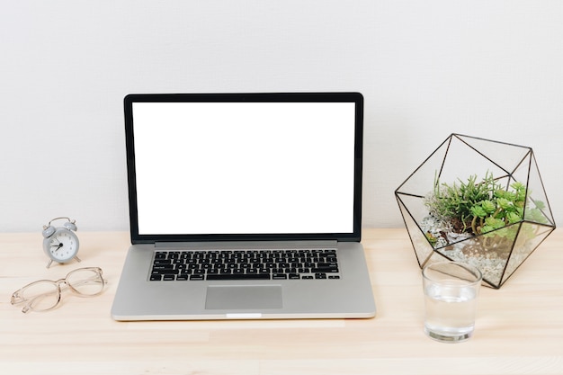 Laptop met groene plant op houten tafel Gratis Foto