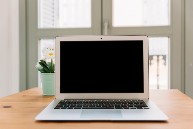 Laptop op tafel in de buurt van plant Gratis Foto