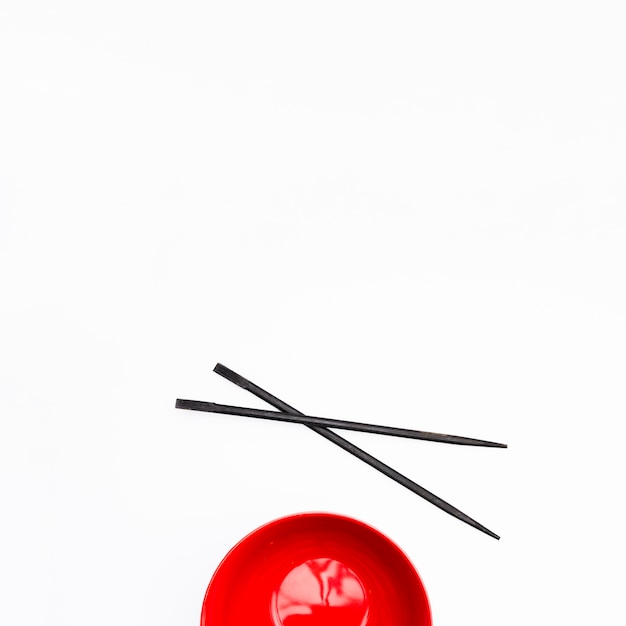 Leeg rood kom en eetstokje dat op witte achtergrond wordt geïsoleerd Gratis Foto