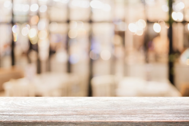 Lege houten tafelblad en wazig bokeh café en restaurent interieur achtergrond. Premium Foto