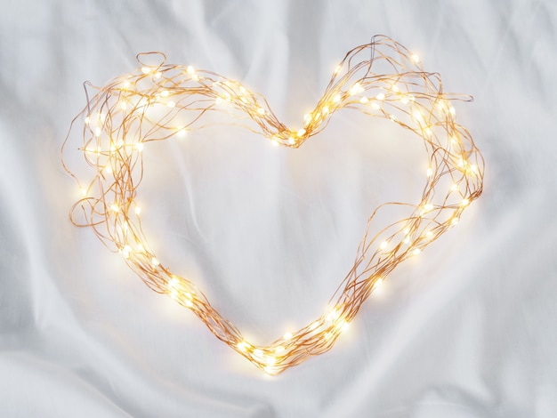 Leidene verlichting en draadkader hartvorm op witte bedsheet Premium Foto