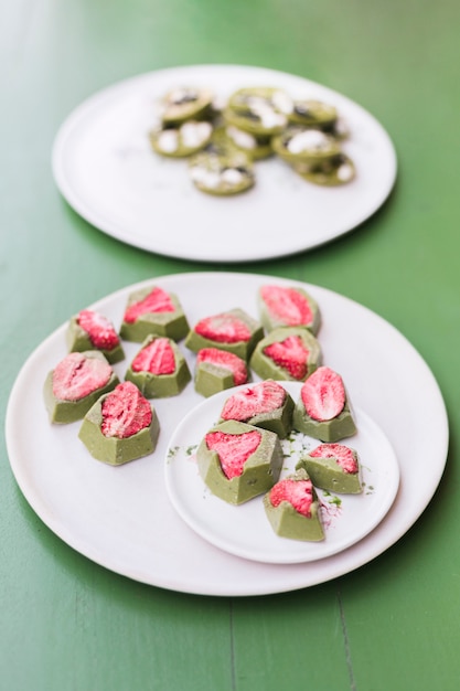 Lekkere desserts met aardbei op witte keramische platen over groene tafel Gratis Foto