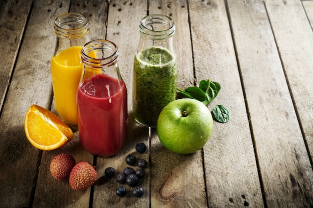 Lekkere, kleurrijke, verse zelfgemaakte smoothies in glazen potjes op houten tafel. gezond, detox concept. Gratis Foto