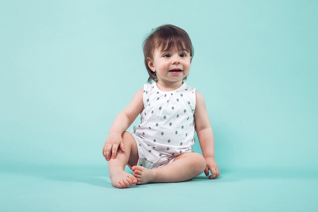 Leuke kleine meisjes kruipende zitting in studio op blauwe achtergrond Premium Foto