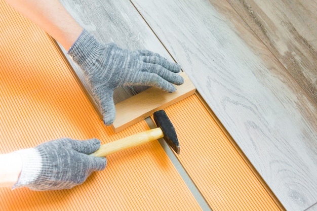 Man legt een nieuwe laminaatvloer. reparatie in het werknemer herstelt de vloer. laminaat legproces | Premium