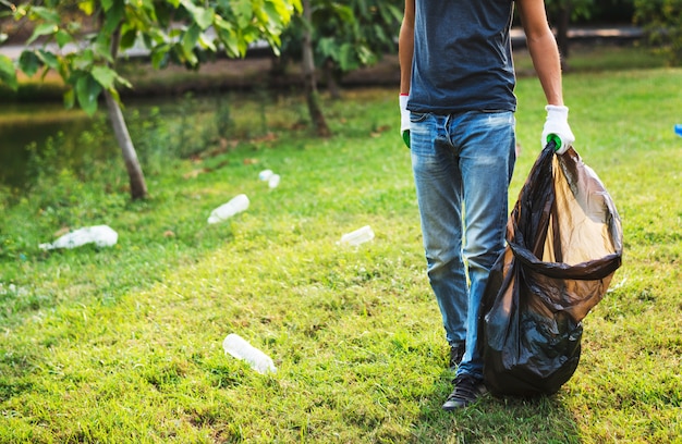 Man met plastic zak pick-up flessen in het park Premium Foto