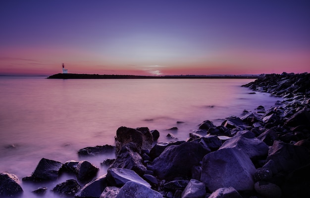 Mangnificzonsondergang bij een lang schot van de overzeese kust Gratis Foto