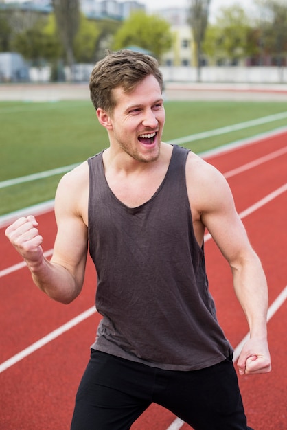 Mannelijke atleet die zijn overwinning op rasspoor viert Gratis Foto