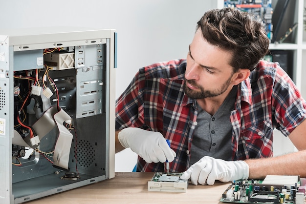 Mannelijke technicus die aan gebroken computer werkt Gratis Foto