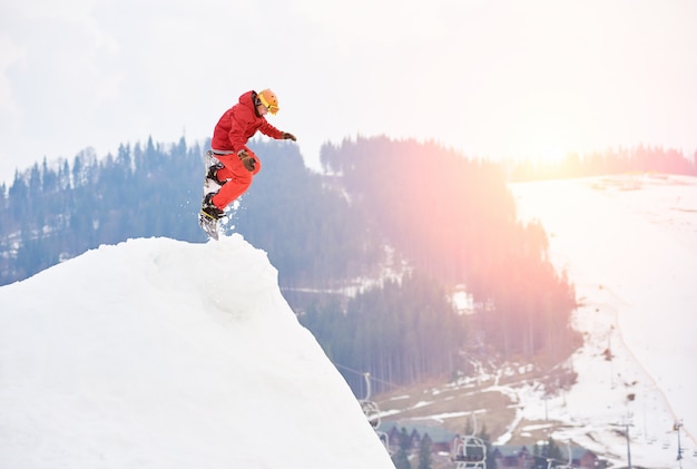 Mens Die Snowboarder Vanaf De Bovenkant Van De Sneeuwheuvel Met Snowboard In De Avond Bij Zonsondergang Springt Premium Foto