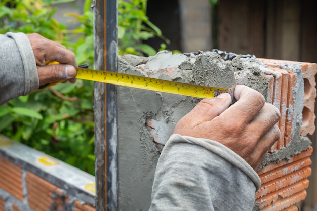 Metselen. bouwvakker die een bakstenen muur bouwt. Gratis Foto