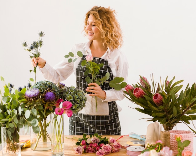 Middelgrote geschotene gelukkige bloemist die bloemen schikken Gratis Foto