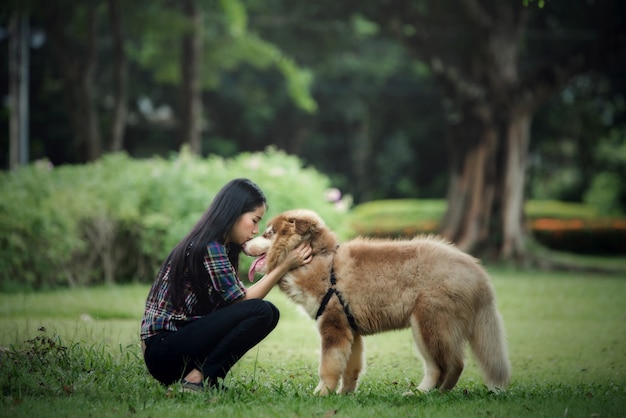 Mooie jonge vrouw die met haar kleine hond in een park in openlucht speelt. levensstijl portret. Gratis Foto