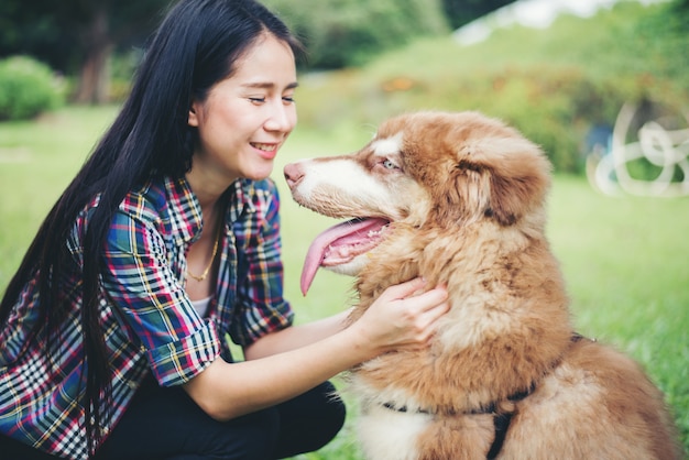 Mooie jonge vrouw die met haar kleine hond in een park in openlucht speelt. levensstijl portret. Gratis Foto