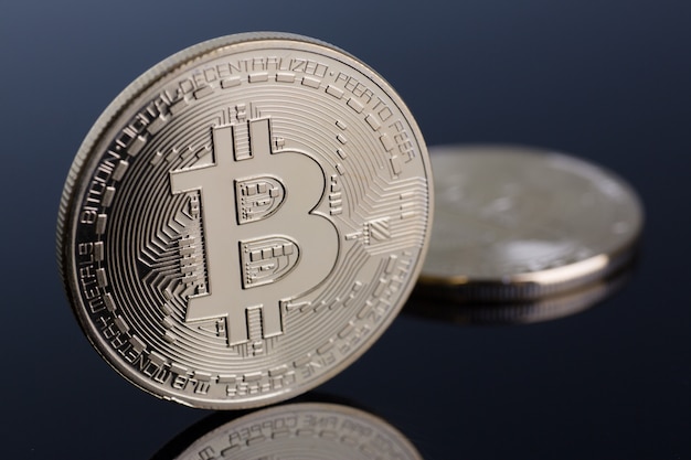 Munt van cryptomunt bitcoin op een grijs-blauwe achtergrond met reflectie onderworpen goud uitwisseling piramide op geld in verband met de groei of val wisselkoers close-up. Premium Foto