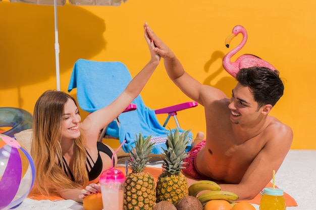 Paar dat op strand met vruchten rust Gratis Foto