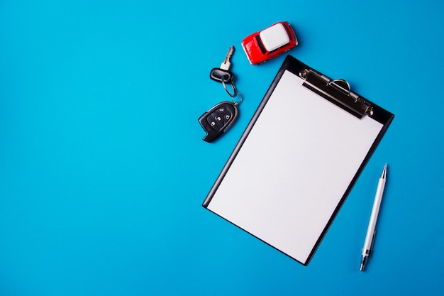 Papier leeg met speelgoed rode auto en sleutels op een blauwe achtergrond. technische keuring of autokrediet Premium Foto