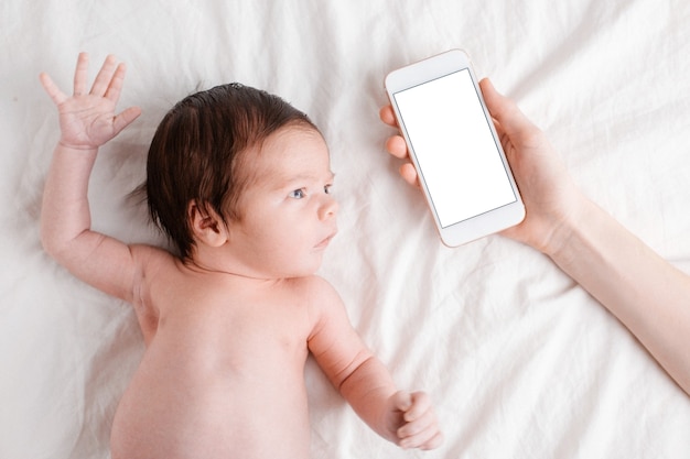 Van streek belediging onpeilbaar Pasgeboren baby op witte bed, vrouw met mobiele telefoon in de hand  bovenaanzicht | Premium Foto