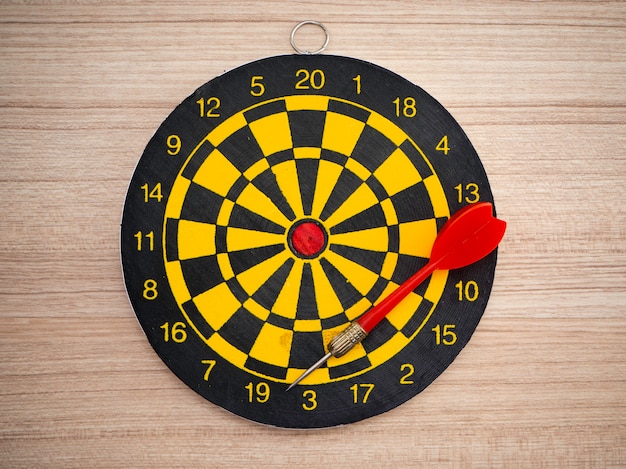 Pijltjepijl en dartboard op bruine houten achtergrond Premium Foto