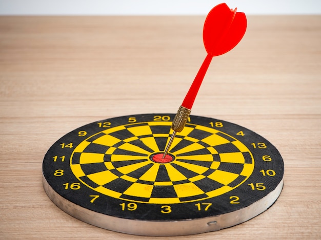 Pijltjepijl en dartboard op bruine houten achtergrond Premium Foto