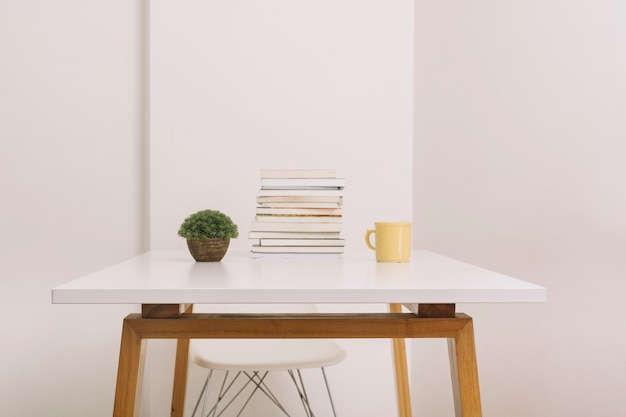 Plant en mok in de buurt van boeken op tafel Gratis Foto