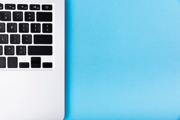 Plat lag laptop op blauwe achtergrond Gratis Foto