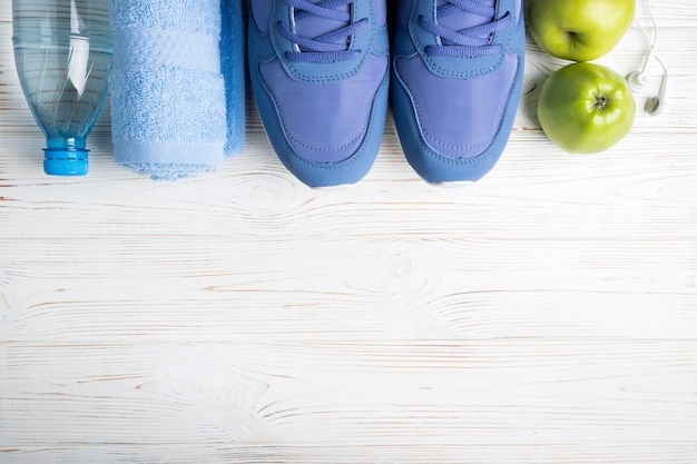 Plat lag sportschoenen, fles water, appels, handdoek en oortelefoons op wit. Premium Foto