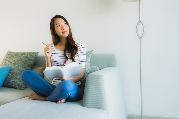Portret mooie jonge aziatische vrouwen die boek met koffiekop lezen Gratis Foto