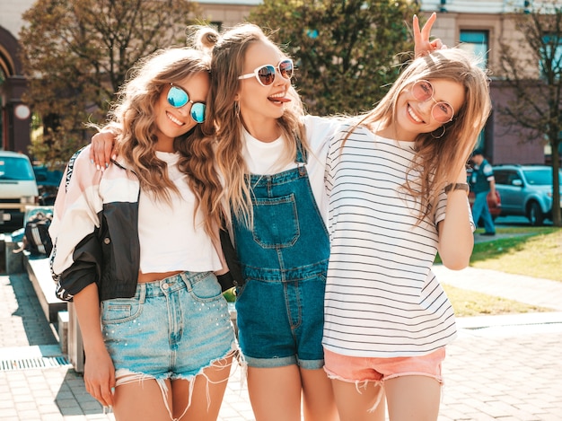 Portret van drie jonge mooie glimlachende hipster meisjes in trendy zomerkleren. sexy zorgeloze vrouwen die zich voordeed op straat. positieve modellen met plezier in een zonnebril Gratis Foto