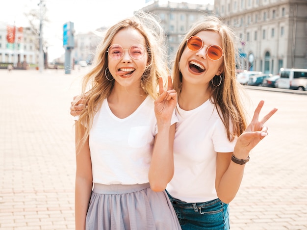 Portret Van Twee Jonge Mooie Blonde Glimlachende Hipster Meisjes In Kleren Van De Trendy De