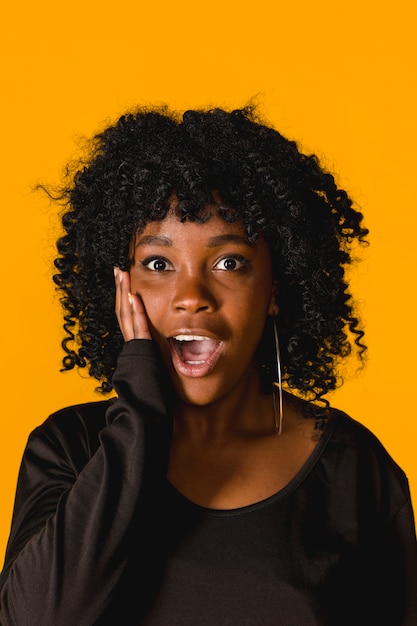Portret van verbaasde jonge afrovrouw op gekleurde achtergrond Gratis Foto