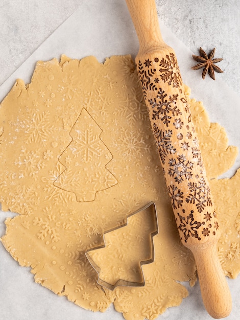Proces van het bakken van traditioneel kerst- en nieuwjaarsdessert, peperkoekkoekjes, deegrol met sneeuwvlokkenpatroon, anijssterren en kaneel, kerstmis en winter, frame-indeling Premium Foto