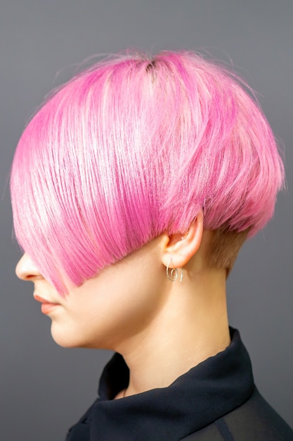 Profiel portret van een jonge blanke vrouw met roze bob kapsel op een grijze achtergrond | Premium Foto