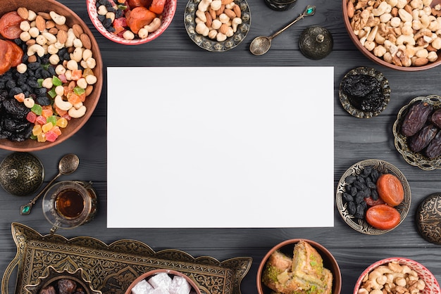 Ramadan kaart omringd met traditionele gedroogde vruchten; data; thee en baklava op tafel Gratis Foto