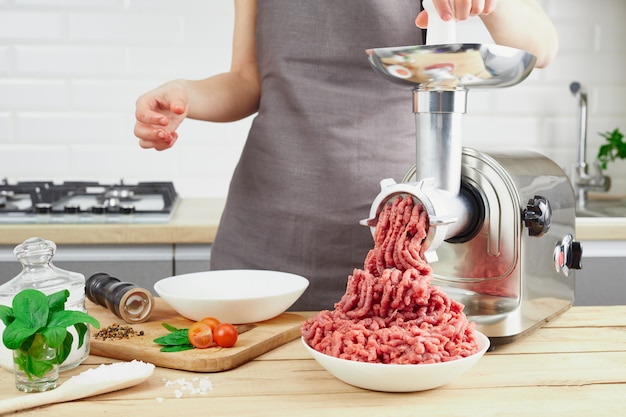 richting Habubu Madison Rauw vlees. het proces van het bereiden van gehakt door middel van een  vleesmolen. de vrouwelijke handen gebruiken vleesbijl bij keuken. | Premium  Foto
