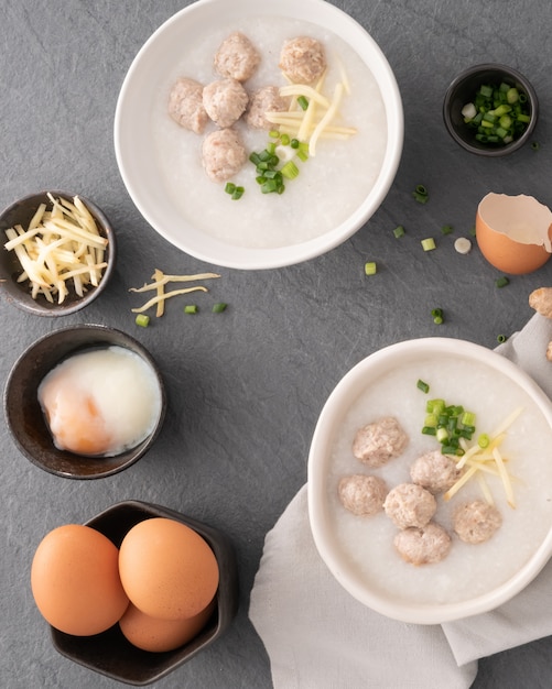 Rijstcongee met fijngehakt varkensvlees in witte kom. kom rijstepap met zacht gekookt ei. aziatisch ontbijt Premium Foto